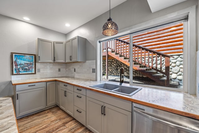 911 Davis, Mccall, ID 83638 - kitchen featuring stainless steel dishwasher, a sink, gray cabinets, light wood-style floors, and backsplash