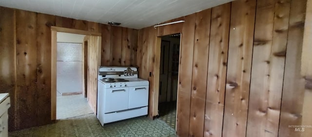 kitchen featuring wooden walls, white stove, and white cabinets