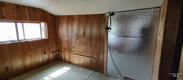 interior space featuring lofted ceiling and wooden walls