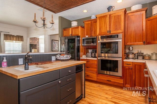 8344 Partridge Dr, Nampa, ID 83686 - kitchen featuring a sink, light wood-style floors, brown cabinets, wood counters, and appliances with stainless steel finishes