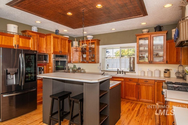 8344 Partridge Dr, Nampa, ID 83686 - kitchen with brown cabinets, light countertops, light wood-style floors, a center island, and appliances with stainless steel finishes