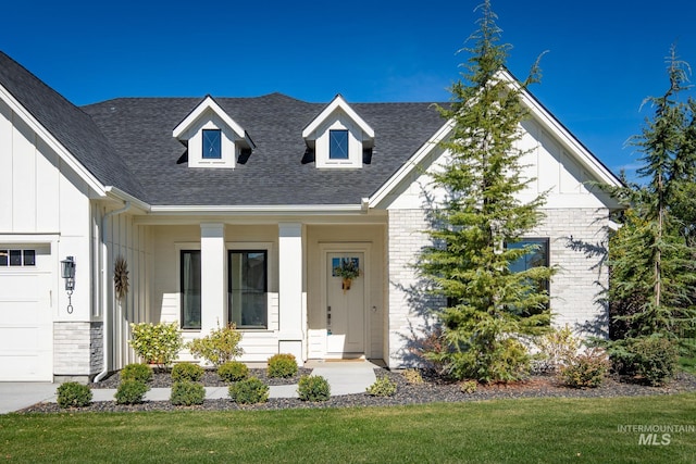 view of front of property with covered porch, a front yard, and a garage