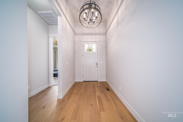 doorway featuring a notable chandelier and light wood-type flooring