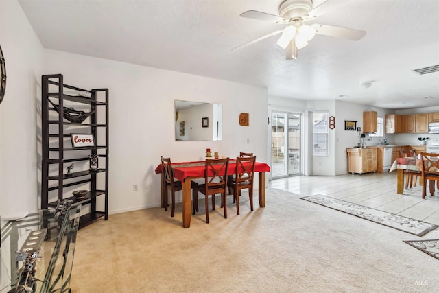 dining space featuring light carpet, ceiling fan, visible vents, and light tile patterned floors