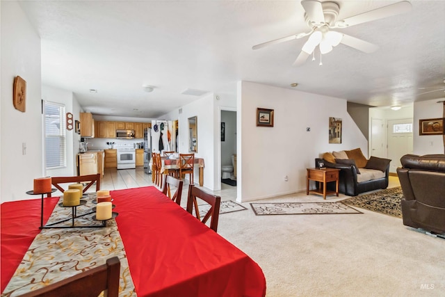 dining room with baseboards, a ceiling fan, and light colored carpet