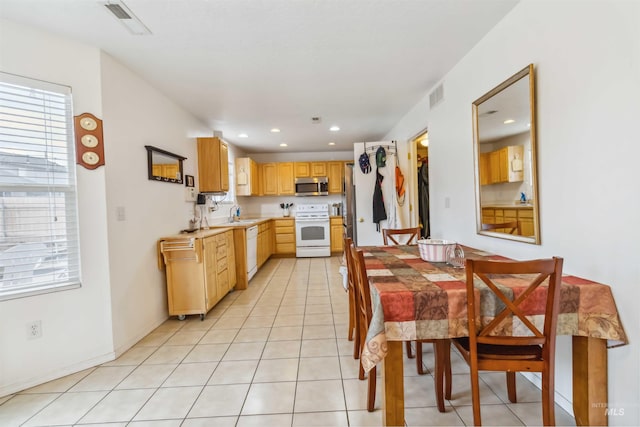 kitchen featuring light tile patterned floors, light brown cabinets, white appliances, visible vents, and light countertops