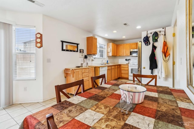 kitchen featuring light brown cabinetry, white appliances, light countertops, and visible vents