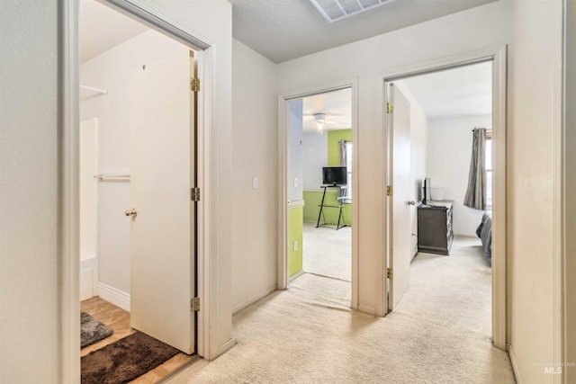 corridor featuring visible vents and light colored carpet