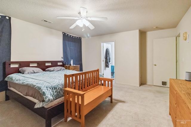 bedroom with a textured ceiling, a ceiling fan, visible vents, and light colored carpet