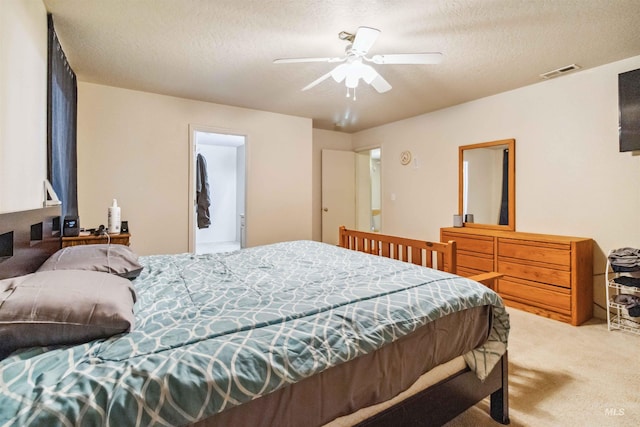 carpeted bedroom featuring a textured ceiling, ceiling fan, and visible vents