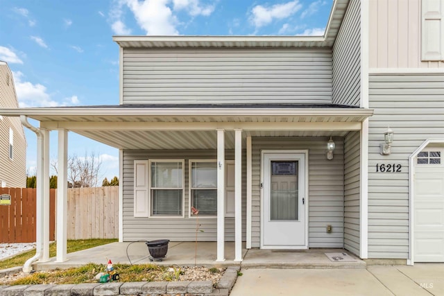 entrance to property featuring covered porch and fence