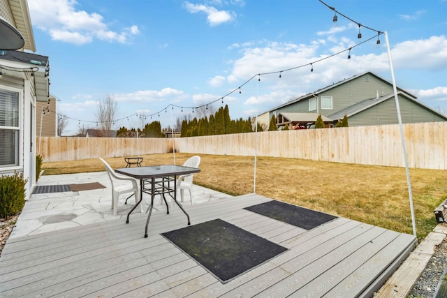 wooden terrace featuring a yard, outdoor dining area, and a fenced backyard