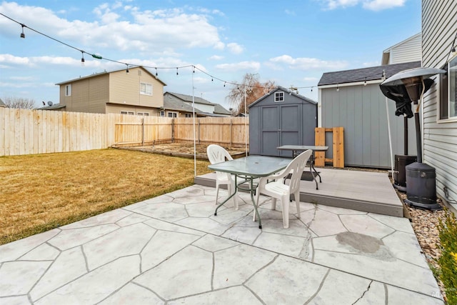 view of patio / terrace with a storage shed, a fenced backyard, outdoor dining area, a wooden deck, and an outdoor structure