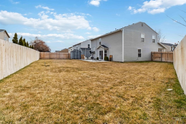 view of yard featuring an outbuilding, a patio area, a fenced backyard, and a shed