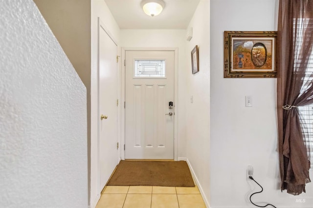 doorway to outside with baseboards and light tile patterned floors