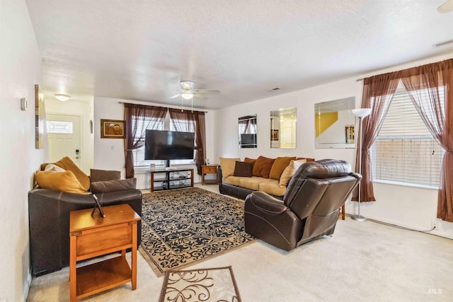 carpeted living area featuring ceiling fan, a textured ceiling, visible vents, and a wealth of natural light