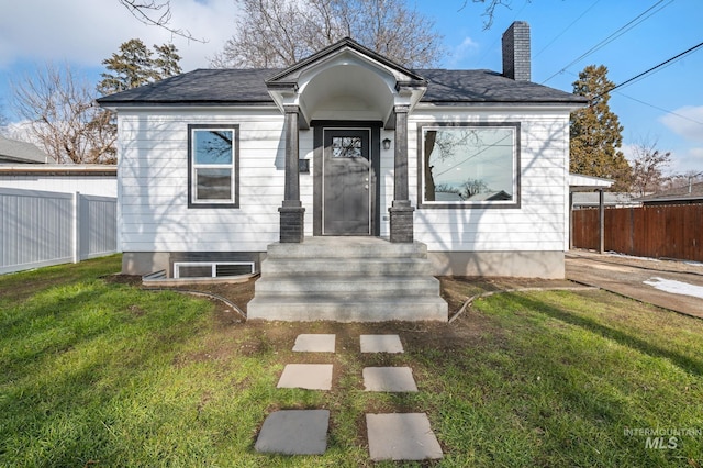 bungalow featuring fence, a chimney, and a front lawn