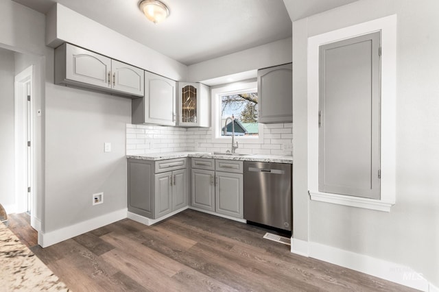 kitchen featuring tasteful backsplash, stainless steel dishwasher, dark wood-type flooring, and gray cabinetry