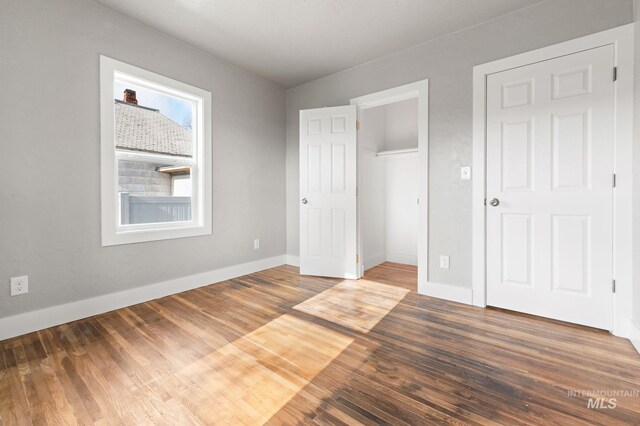 unfurnished bedroom featuring a closet, wood finished floors, and baseboards