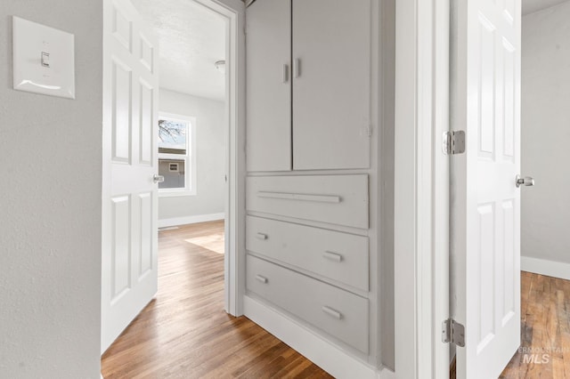 hall with baseboards and wood finished floors