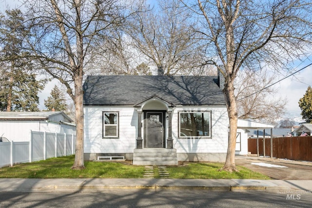 bungalow featuring driveway, a shingled roof, a front lawn, and fence