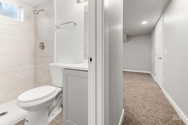 bathroom featuring baseboards, a tile shower, vanity, and toilet