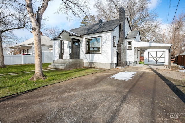 bungalow-style home featuring a garage, a front lawn, a chimney, and fence