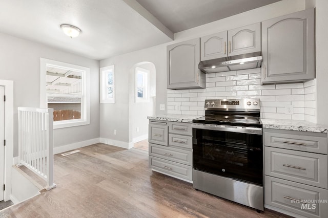 kitchen featuring gray cabinets, a wealth of natural light, electric stove, and under cabinet range hood