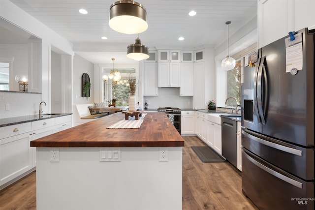 kitchen with hanging light fixtures, a kitchen island, stainless steel appliances, and butcher block countertops