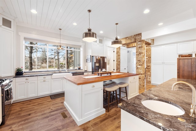 kitchen with butcher block counters, a kitchen island, and white cabinets