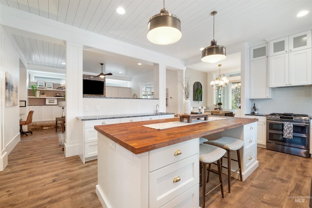 kitchen featuring a center island, double oven range, wooden counters, and white cabinetry