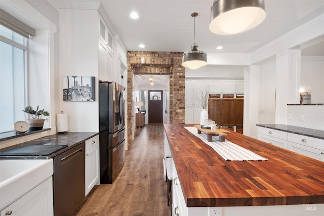 kitchen featuring black dishwasher, wooden counters, hanging light fixtures, a center island, and stainless steel fridge