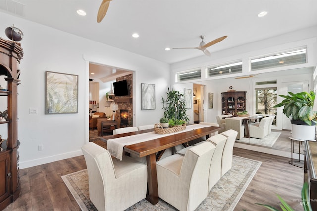 dining room featuring ceiling fan, a fireplace, wood finished floors, and visible vents