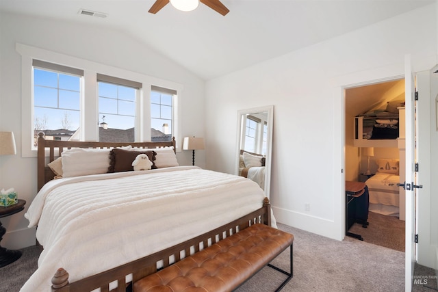 carpeted bedroom featuring lofted ceiling, a ceiling fan, visible vents, baseboards, and a walk in closet