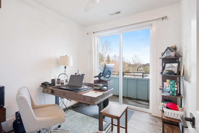 office area with light wood finished floors, visible vents, and a ceiling fan