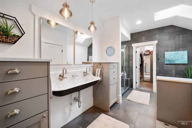 full bathroom with vaulted ceiling with skylight, a shower stall, a sink, and recessed lighting