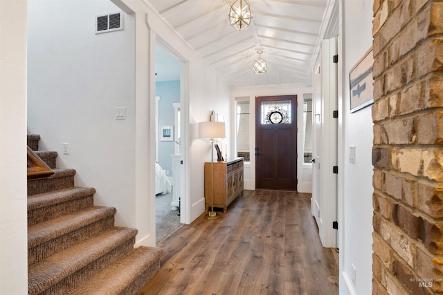 entrance foyer with dark wood-style floors, vaulted ceiling, stairs, and visible vents