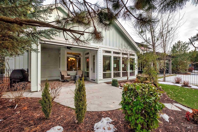 back of property featuring a patio area, ceiling fan, fence, and board and batten siding