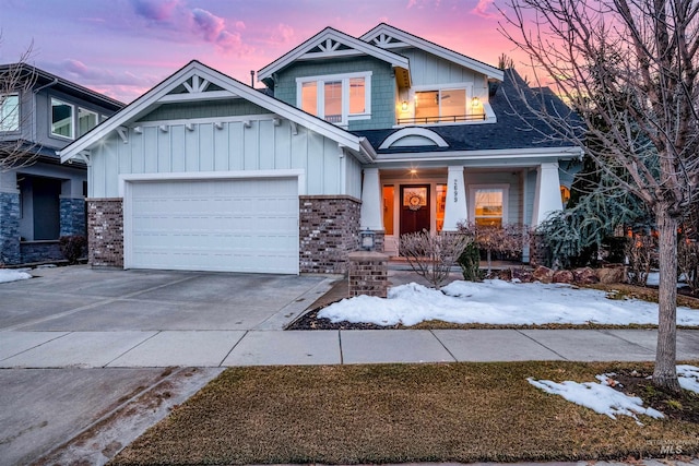 craftsman-style home with driveway, roof with shingles, an attached garage, board and batten siding, and brick siding