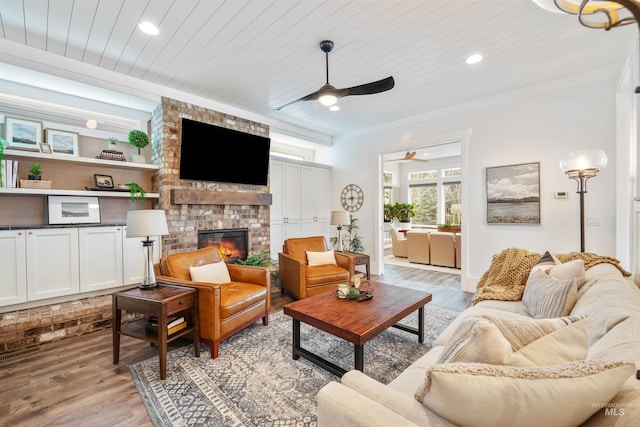 living area with ceiling fan, recessed lighting, wood ceiling, a brick fireplace, and light wood finished floors