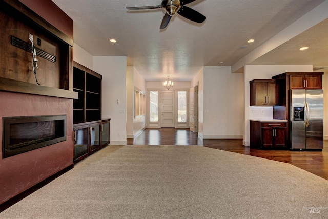 living room featuring ceiling fan with notable chandelier and dark hardwood / wood-style flooring