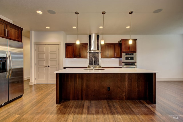 kitchen with pendant lighting, stainless steel appliances, wall chimney range hood, and hardwood / wood-style flooring