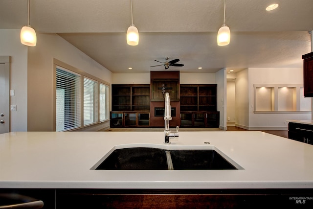 kitchen featuring ceiling fan, decorative light fixtures, a kitchen island with sink, and sink