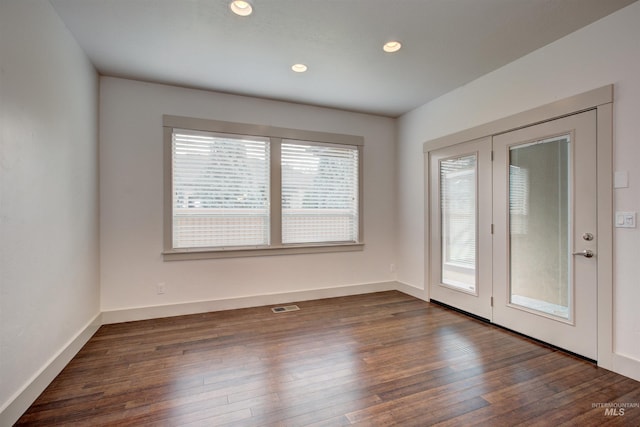 empty room with dark hardwood / wood-style flooring and plenty of natural light