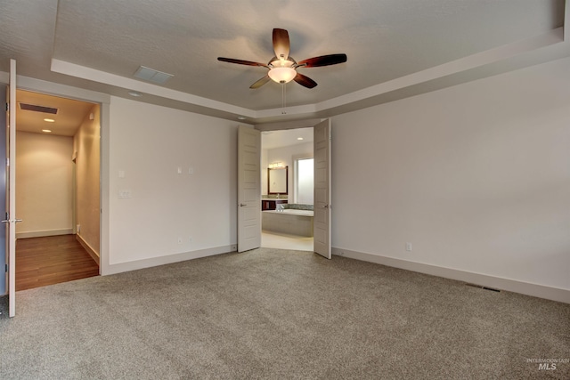 spare room featuring a tray ceiling, ceiling fan, and carpet