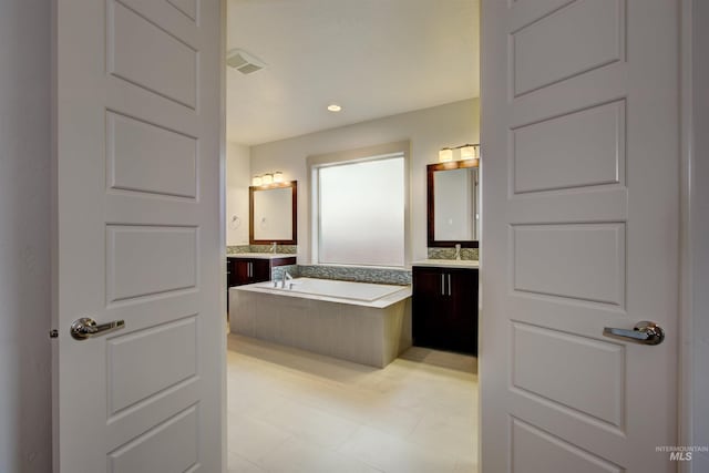 bathroom featuring vanity and tiled bath