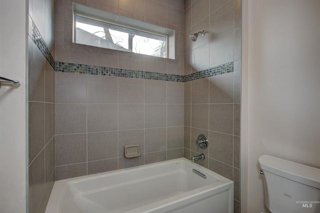 bathroom with tiled shower / bath combo and toilet