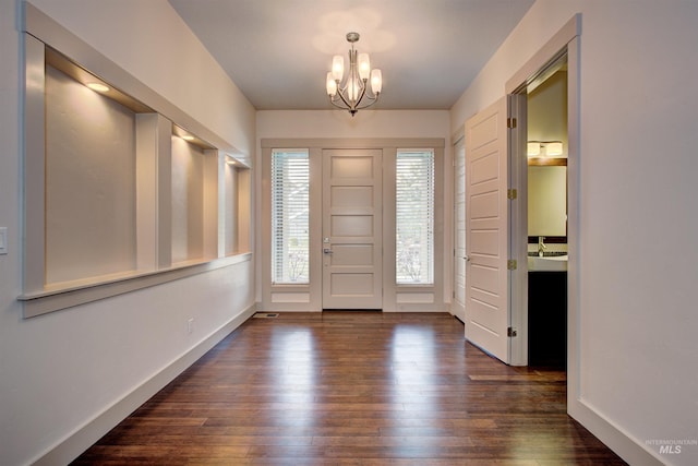 entryway with dark hardwood / wood-style flooring and an inviting chandelier