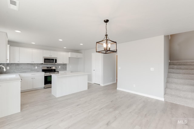 2351 W Opalite Dr, Kuna, ID 83634 - kitchen featuring stainless steel appliances, a center island, open floor plan, decorative backsplash, and white cabinetry
