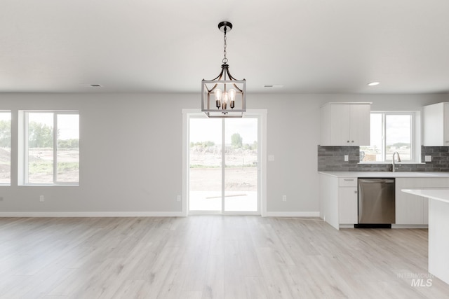 2351 W Opalite Dr, Kuna, ID 83634 - kitchen with stainless steel dishwasher, light wood-style floors, white cabinetry, a chandelier, and decorative backsplash